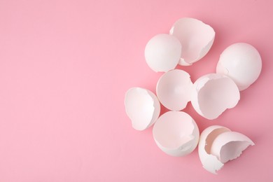 Photo of Broken eggshells on pink background, top view. Space for text