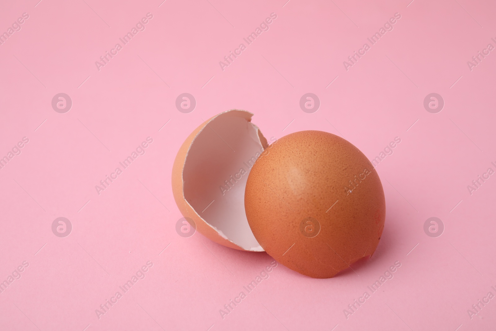 Photo of Pieces of broken eggshells on pink background, closeup