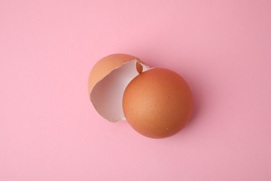 Photo of Pieces of broken eggshells on pink background, above view