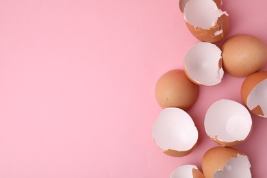 Photo of Broken eggshells on pink background, top view. Space for text