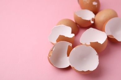 Photo of Broken eggshells on pink background, closeup. Space for text