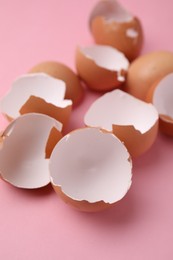 Photo of Pieces of broken eggshells on pink background, closeup