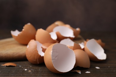 Photo of Pieces of broken eggshells on wooden table, closeup