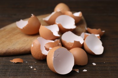 Photo of Pieces of broken eggshells on wooden table, closeup