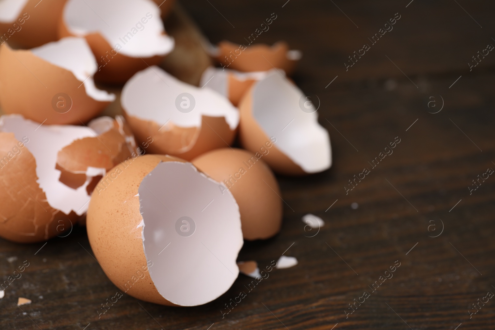 Photo of Pieces of broken eggshells on wooden table, closeup. Space for text