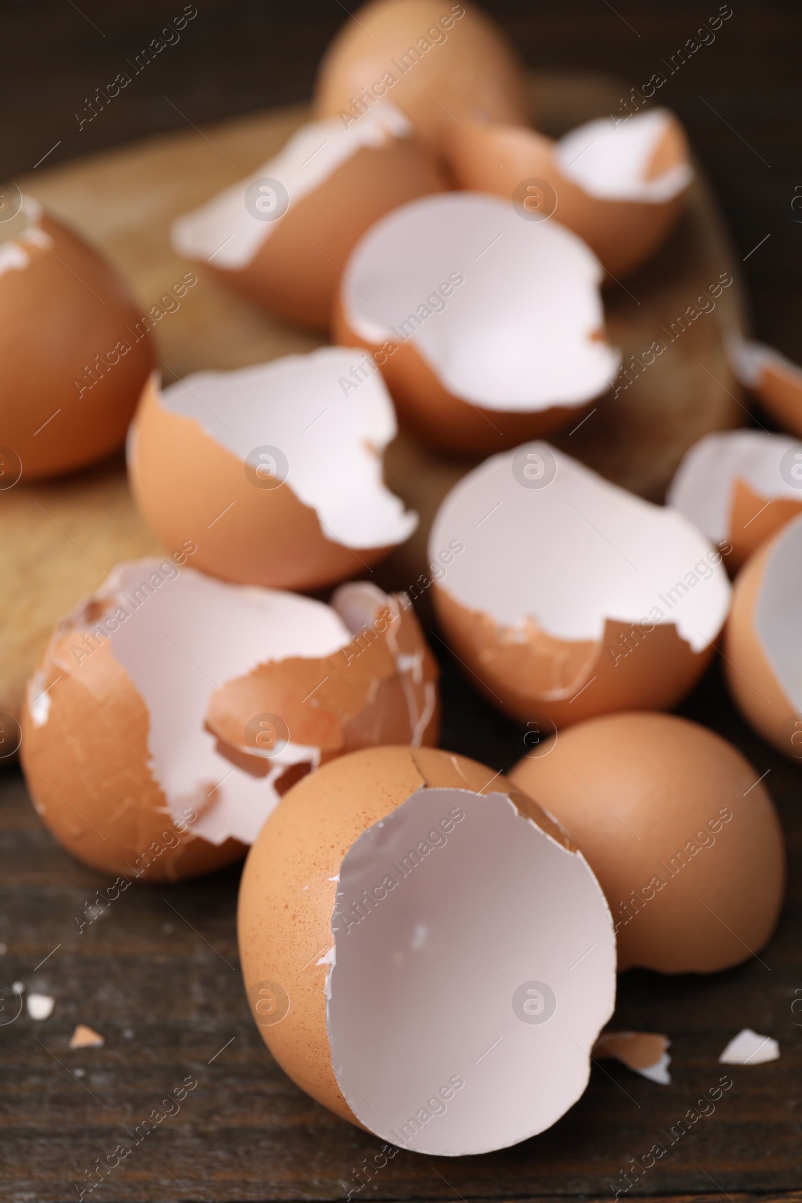 Photo of Pieces of broken eggshells on wooden table, closeup