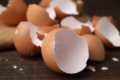 Photo of Pieces of broken eggshells on wooden table, closeup