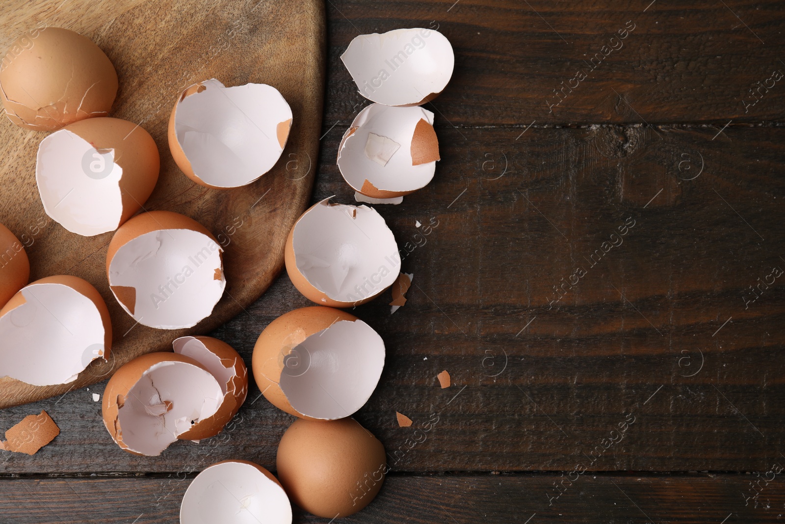 Photo of Broken eggshells on wooden table, top view. Space for text