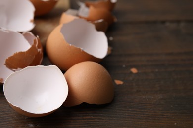 Photo of Pieces of broken eggshells on wooden table, closeup. Space for text