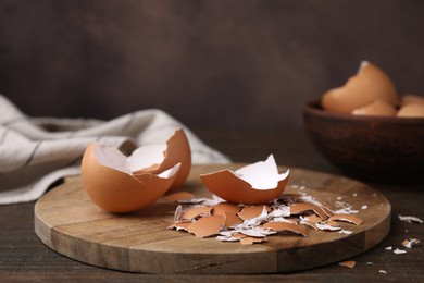 Photo of Pieces of broken eggshells on wooden table, closeup