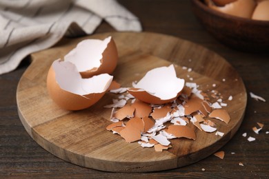 Photo of Pieces of broken eggshells on wooden table, closeup