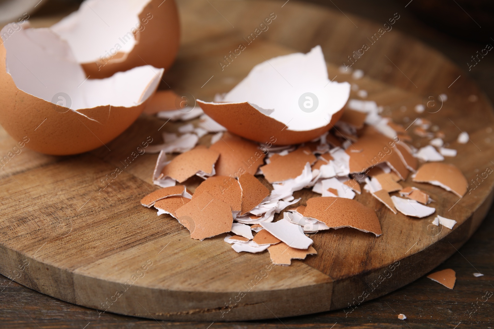 Photo of Pieces of broken eggshells on wooden table, closeup