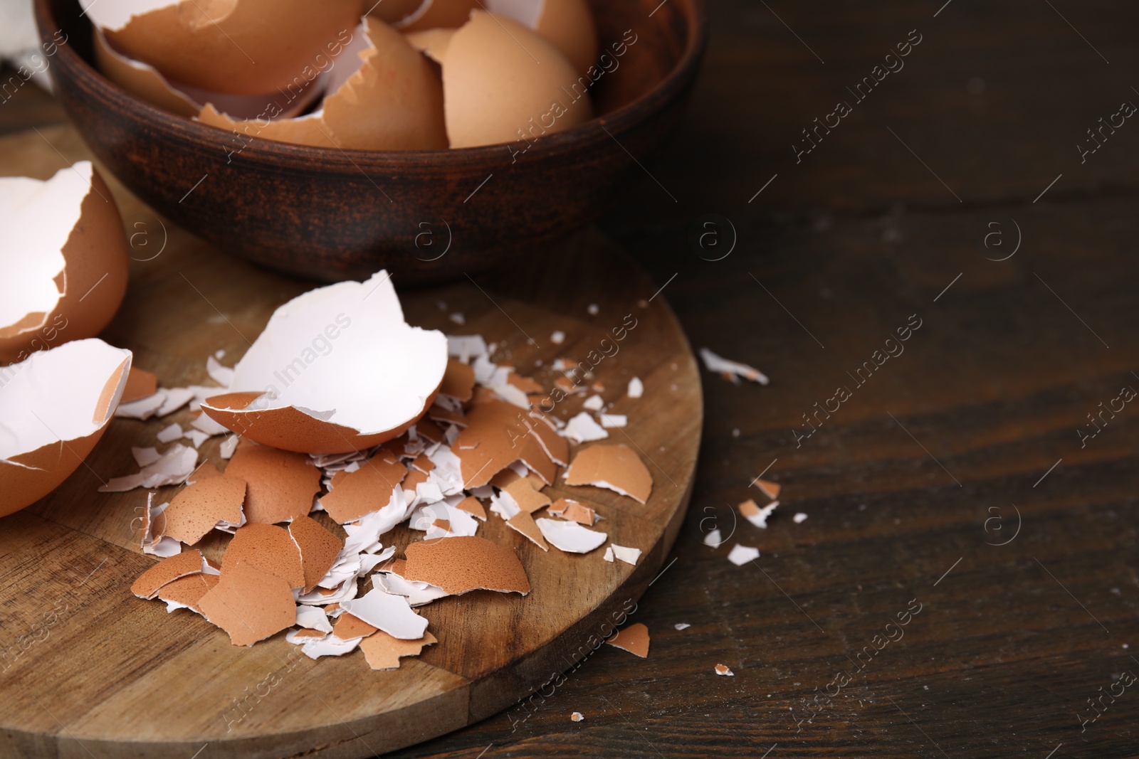 Photo of Pieces of broken eggshells on wooden table, closeup. Space for text