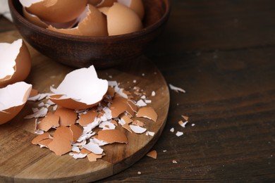 Photo of Pieces of broken eggshells on wooden table, closeup. Space for text