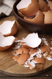 Photo of Pieces of broken eggshells on wooden table, closeup