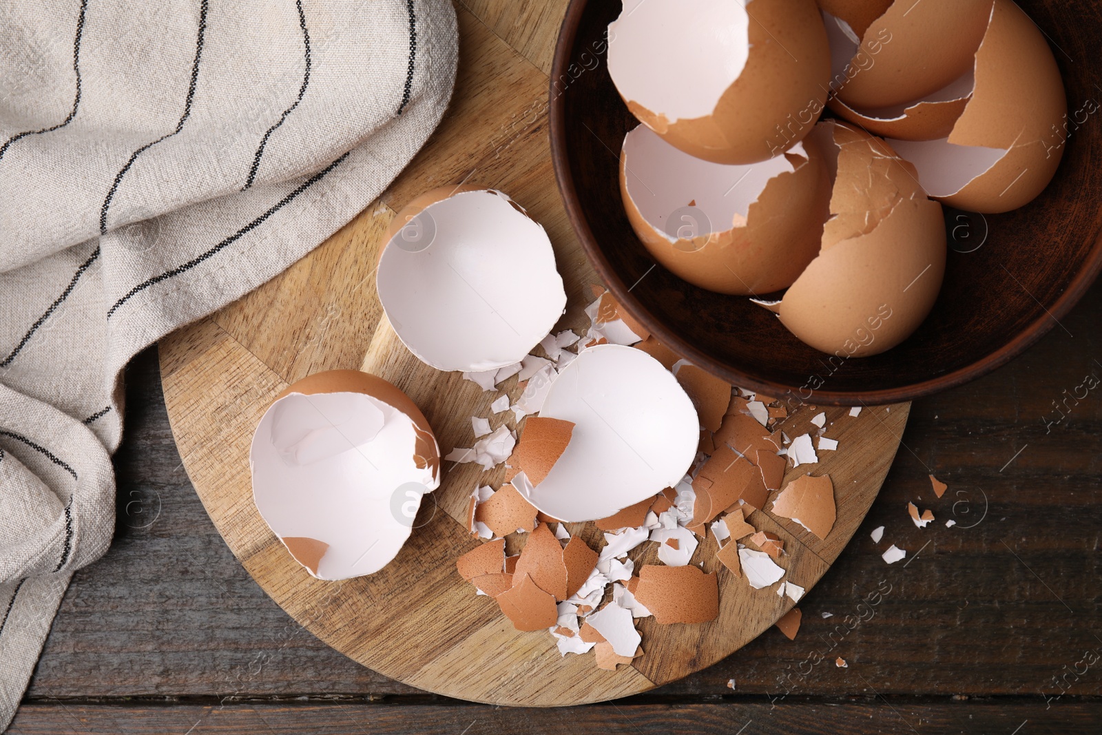 Photo of Pieces of broken eggshells on wooden table, top view