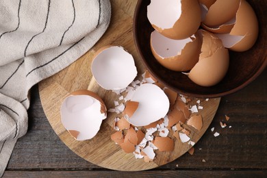 Photo of Pieces of broken eggshells on wooden table, top view