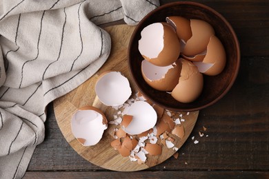 Photo of Pieces of broken eggshells on wooden table, top view