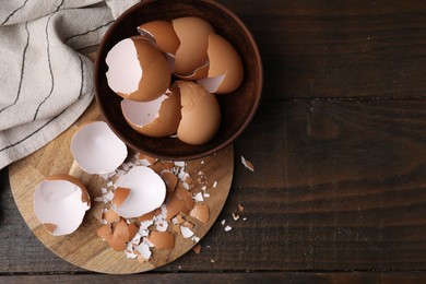 Photo of Pieces of broken eggshells on wooden table, top view. Space for text