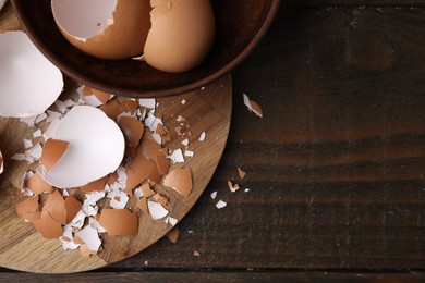 Photo of Pieces of broken eggshells on wooden table, top view. Space for text