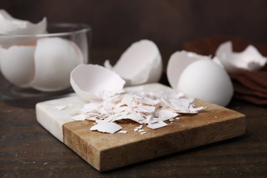 Photo of Pieces of broken eggshells on wooden table, closeup