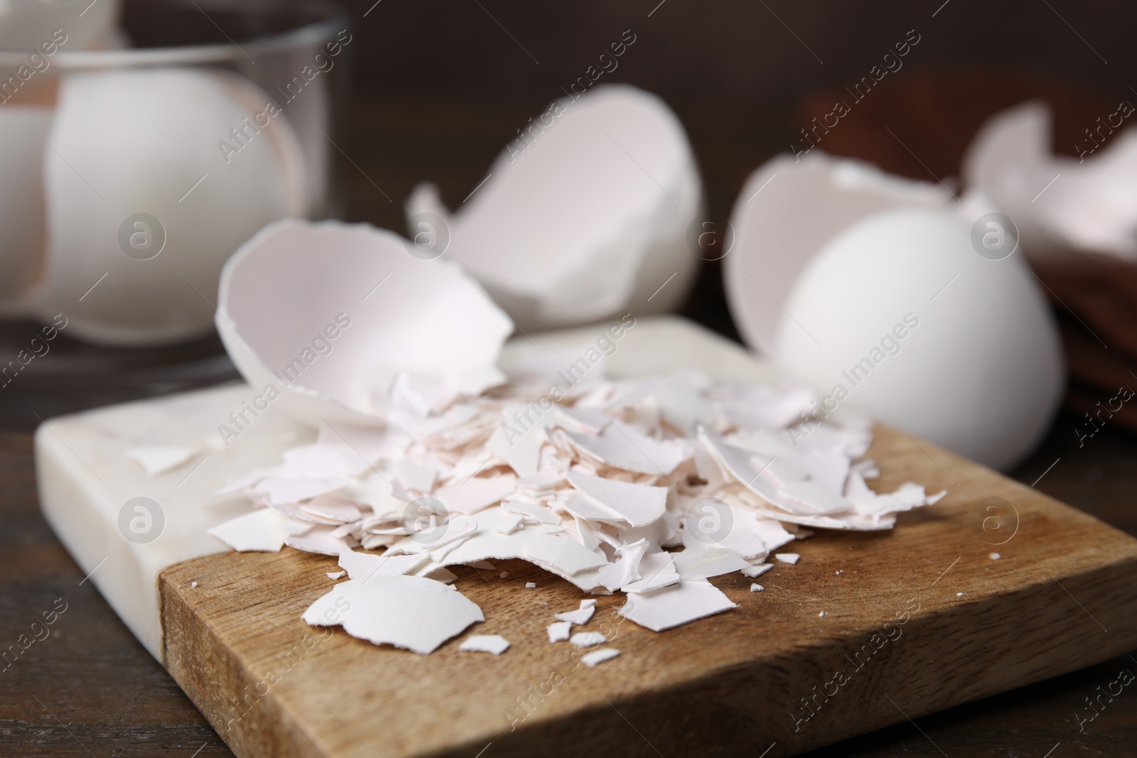 Photo of Pieces of broken eggshells on wooden table, closeup