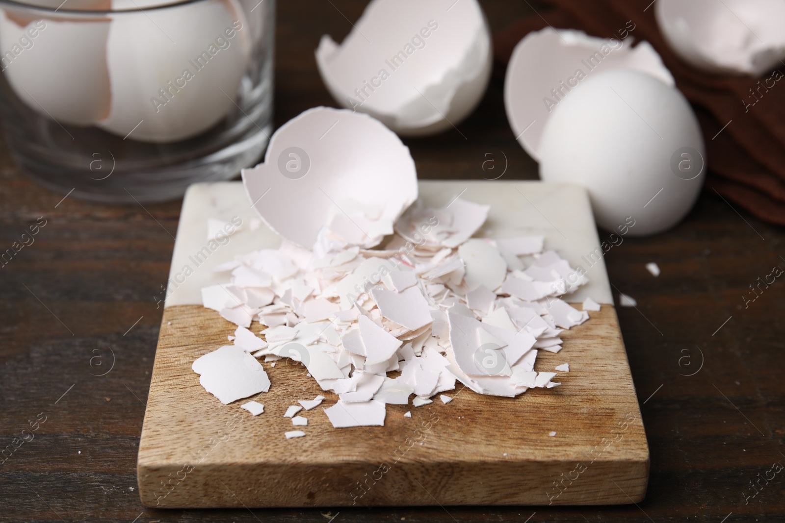 Photo of Pieces of broken eggshells on wooden table, closeup