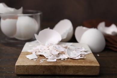 Photo of Pieces of broken eggshells on wooden table, closeup