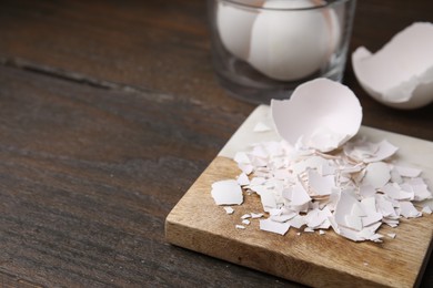 Photo of Pieces of broken eggshells on wooden table, closeup. Space for text