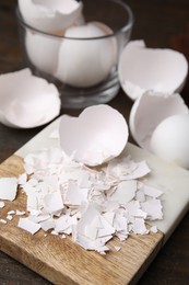 Photo of Pieces of broken eggshells on wooden table, closeup