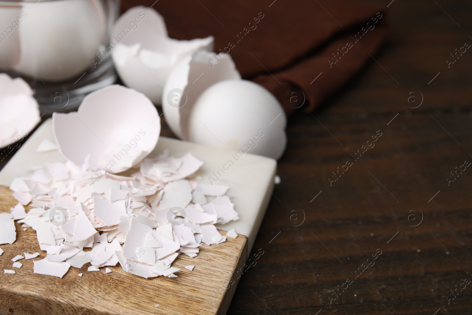 Photo of Pieces of broken eggshells on wooden table, closeup. Space for text