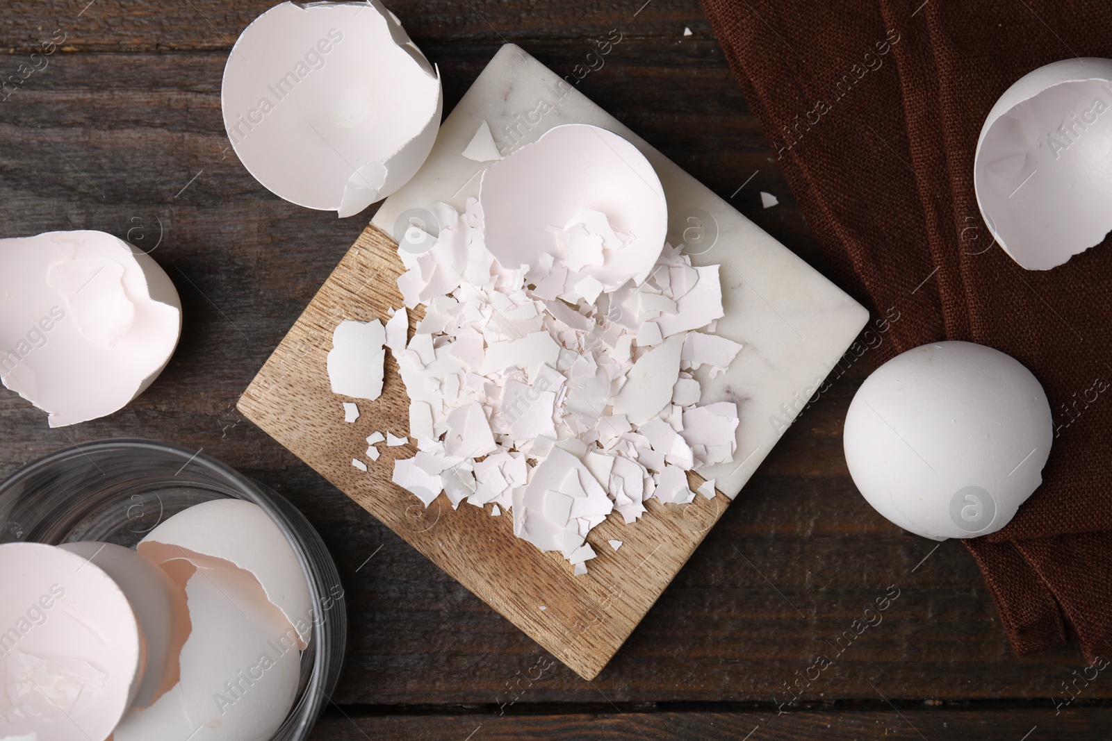 Photo of Pieces of broken eggshells on wooden table, flat lay