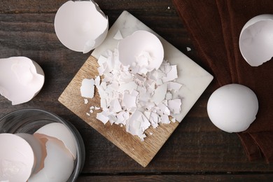 Photo of Pieces of broken eggshells on wooden table, flat lay