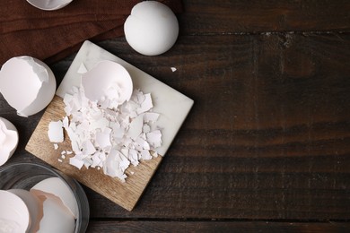 Photo of Pieces of broken eggshells on wooden table, flat lay. Space for text