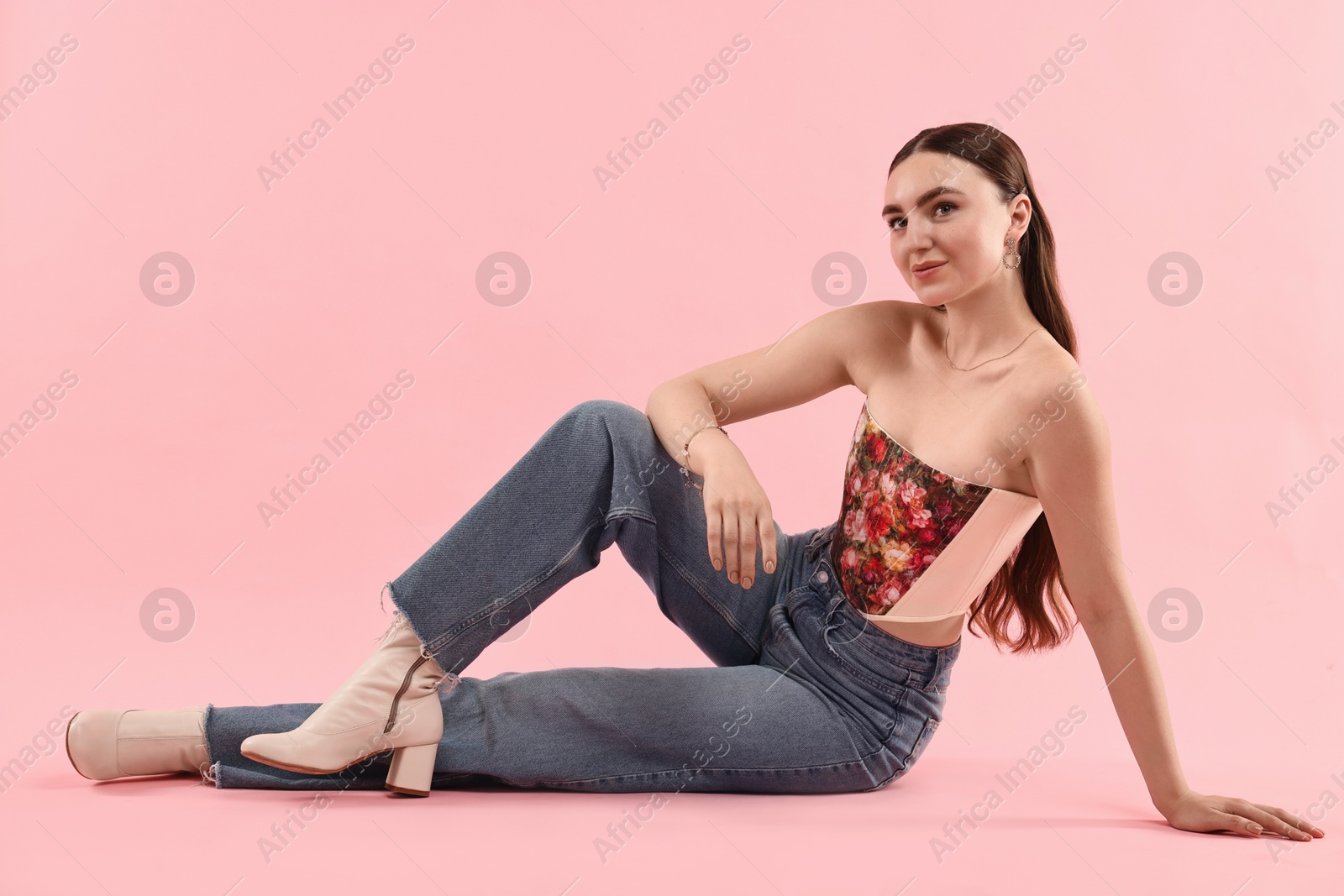 Photo of Beautiful woman in stylish corset posing on pink background