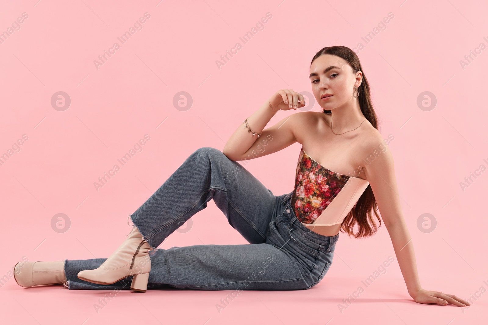 Photo of Beautiful woman in stylish corset posing on pink background