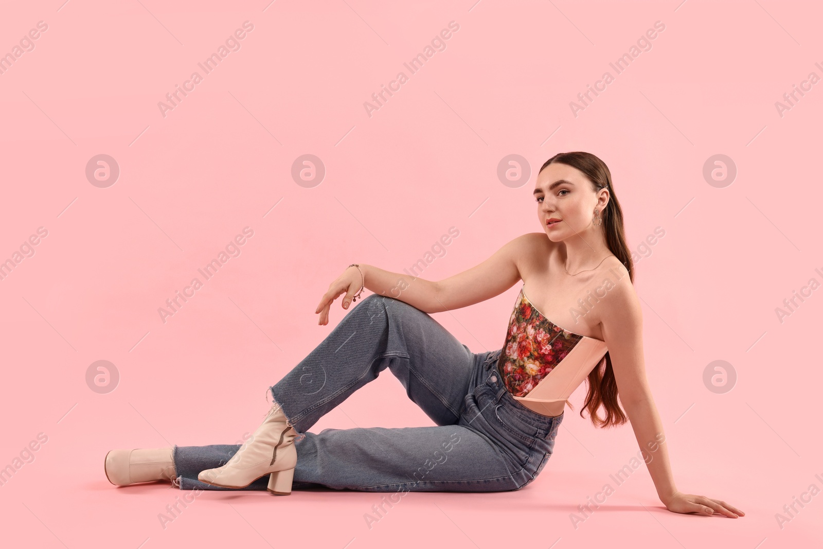 Photo of Beautiful woman in stylish corset posing on pink background