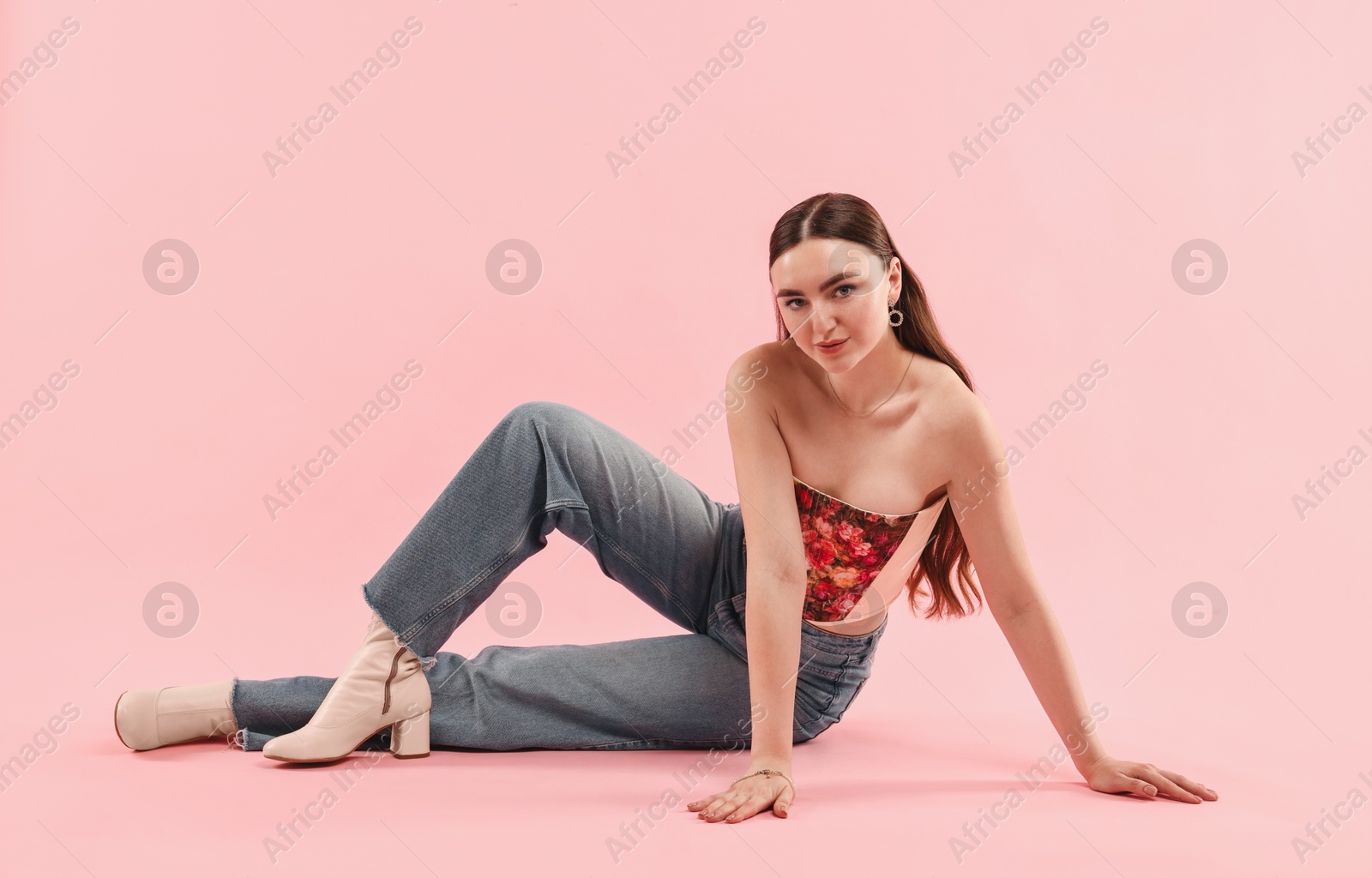 Photo of Beautiful woman in stylish corset posing on pink background