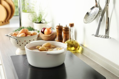 Photo of Boiling potatoes in pot on stove in kitchen