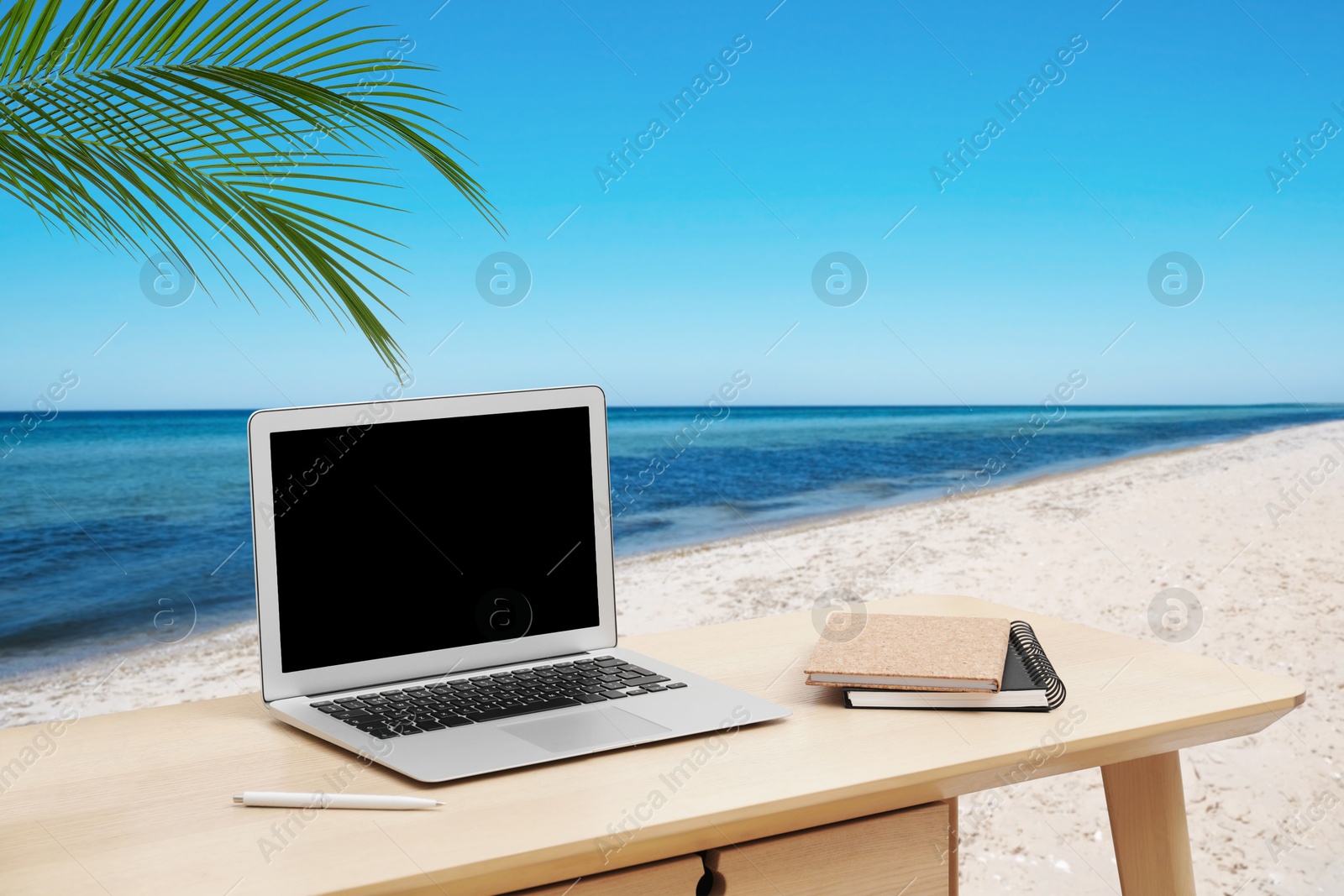 Image of Workplace at beach, distant office. Table with laptop on sandy seashore. Mockup for design