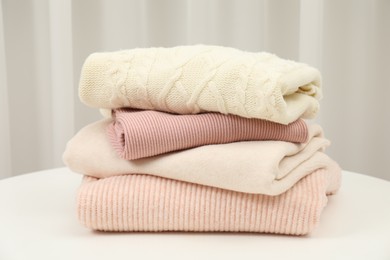 Photo of Stack of clothes on white table indoors