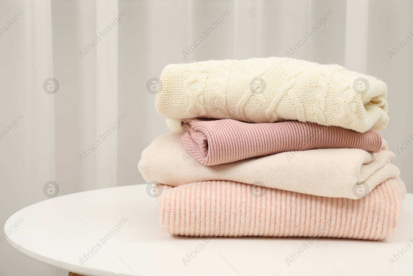 Photo of Stack of clothes on white table indoors, space for text