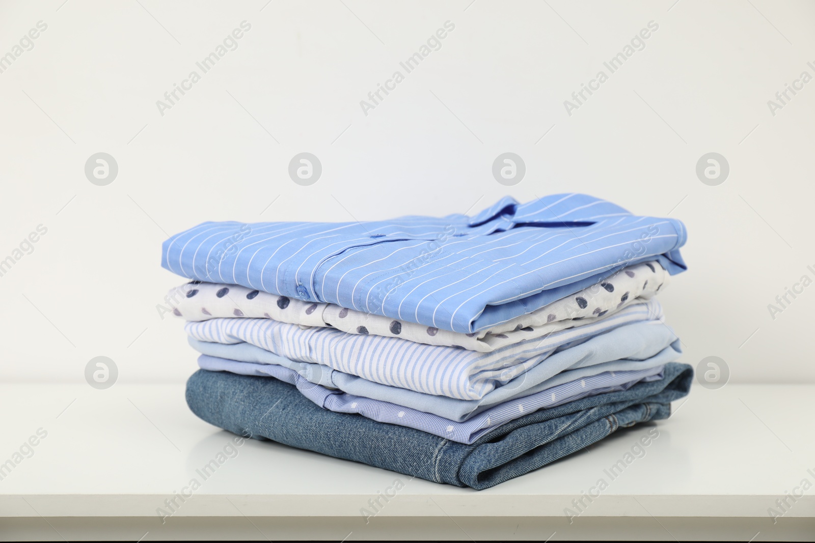 Photo of Stack of clothes on white shelf indoors