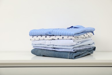 Photo of Stack of clothes on white shelf indoors