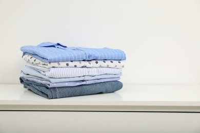 Stack of clothes on white shelf indoors, space for text