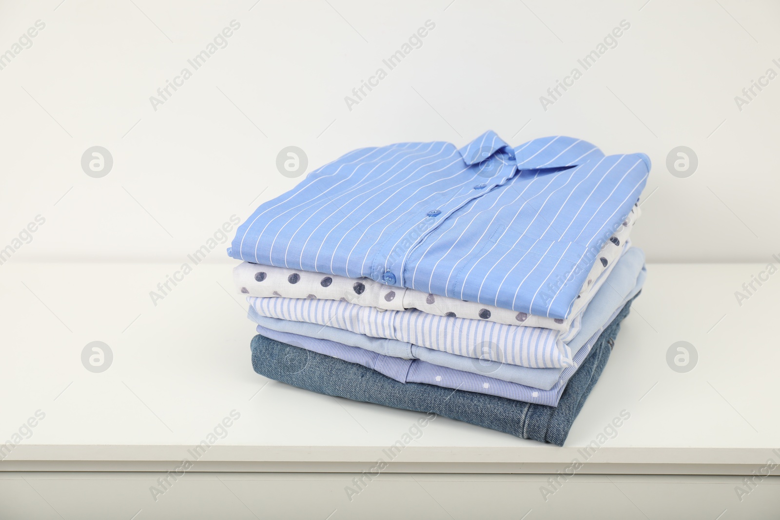 Photo of Stack of clothes on white shelf indoors