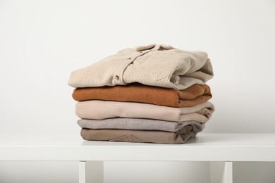 Photo of Stack of clothes on white shelf indoors