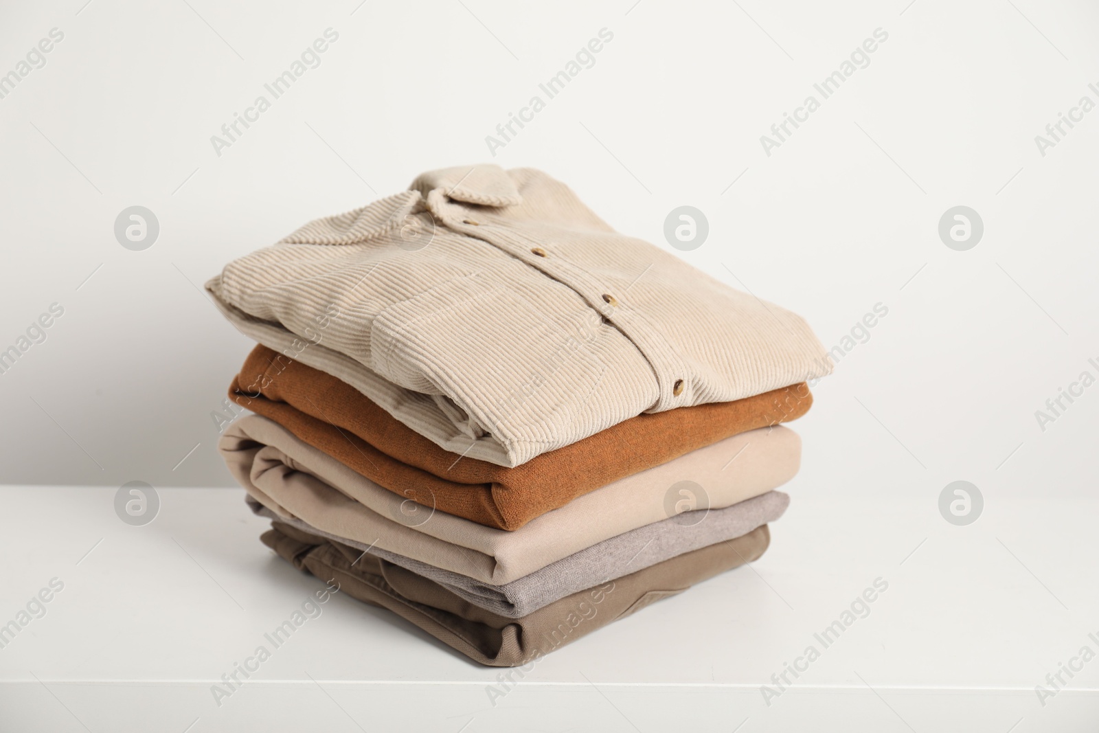 Photo of Stack of clothes on white shelf indoors