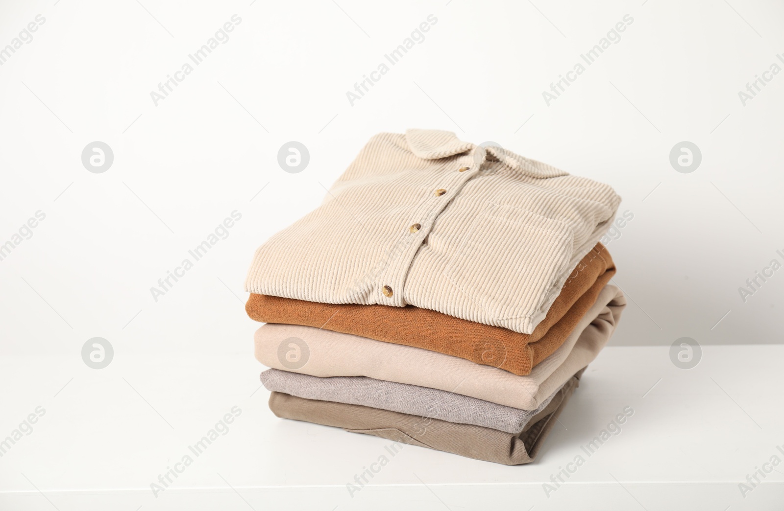 Photo of Stack of clothes on white shelf indoors