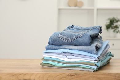 Photo of Stack of clothes on wooden table indoors, space for text